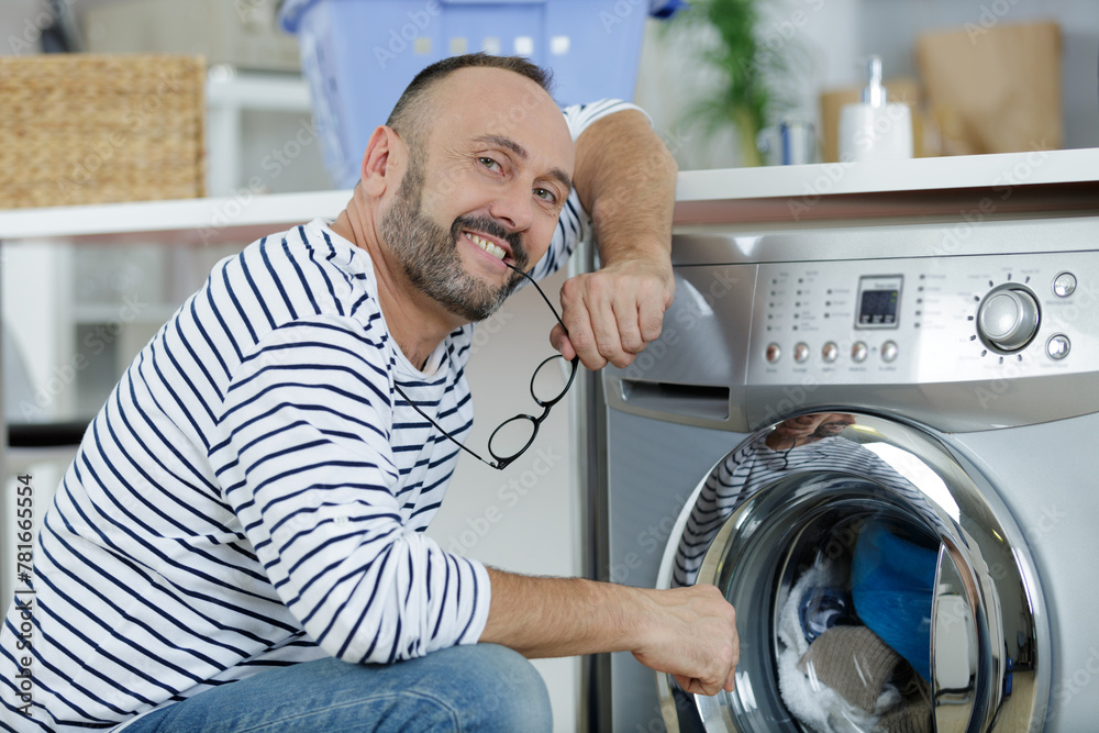 man loading clothes into washing machine man loading clothes into washing machine