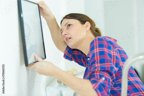 woman hanging a picture on the wall