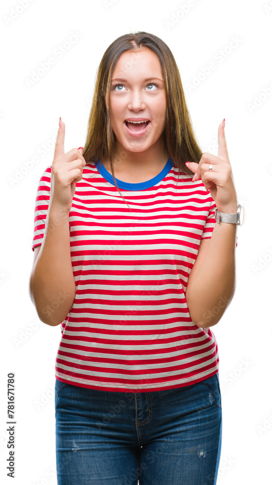 Young caucasian beautiful woman over isolated background amazed and surprised looking up and pointing with fingers and raised arms. Young caucasian beautiful woman over isolated background amazed and surprised looking up and pointing with fingers and raised arms.