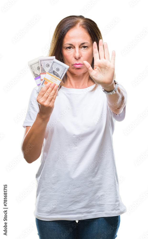 Middle age hispanic woman holding bunch of dollars over isolated background with open hand doing stop sign with serious and confident expression, defense gesture Middle age hispanic woman holding bunch of dollars over isolated background with open hand doing stop sign with serious and confident expression, defense gesture