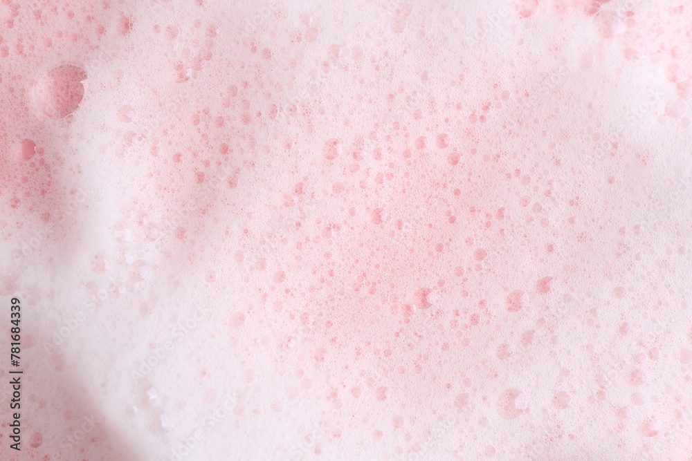 Fototapeta premium White fluffy foam on pink background, top view