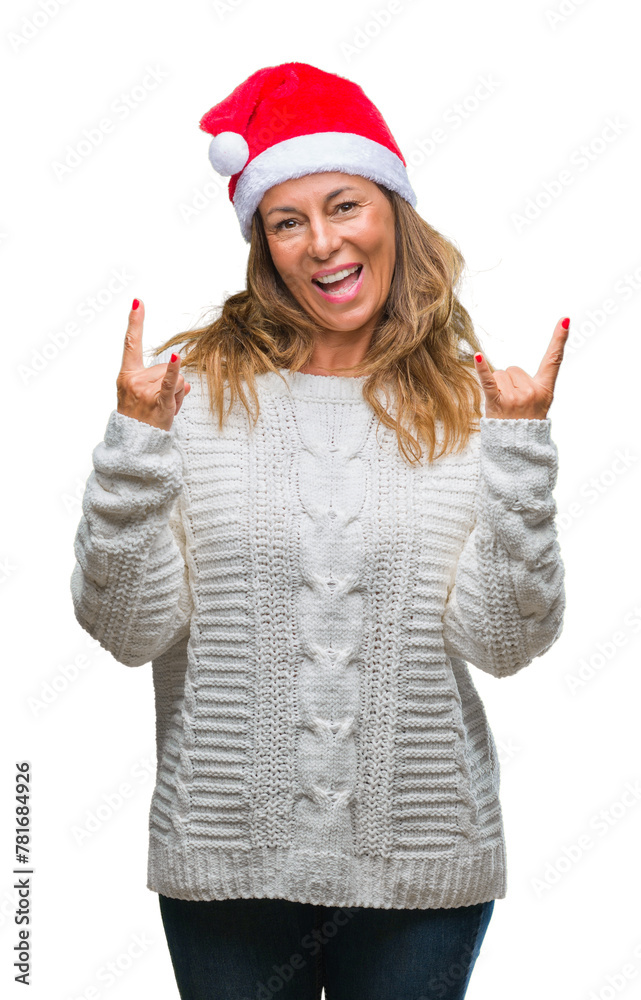 Middle age senior hispanic woman wearing christmas hat over isolated background shouting with crazy expression doing rock symbol with hands up. Music star. Heavy concept. Middle age senior hispanic woman wearing christmas hat over isolated background shouting with crazy expression doing rock symbol with hands up. Music star. Heavy concept.