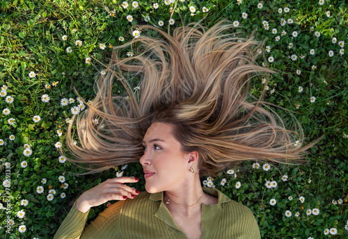 Beautiful blonde girl with beautiful long hair laying in the grass, spring time, beauty portrait photo