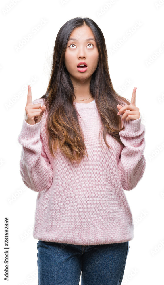 Young asian woman over isolated background amazed and surprised looking up and pointing with fingers and raised arms. Young asian woman over isolated background amazed and surprised looking up and pointing with fingers and raised arms.