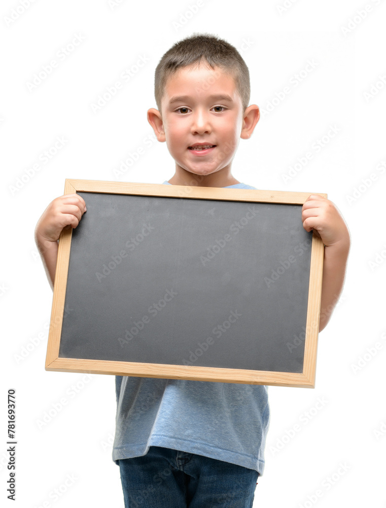 Dark haired little child holding a blackboard with a happy face standing and smiling with a confident smile showing teeth Dark haired little child holding a blackboard with a happy face standing and smiling with a confident smile showing teeth