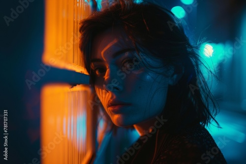 Ethereal portrait of a young woman in blue neon light, capturing a contemplative moment that merges urban vibe with intimate mood.

