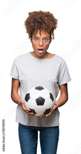 Young african american woman holding soccer football ball over isolated background scared in shock with a surprise face, afraid and excited with fear expression © Krakenimages.com