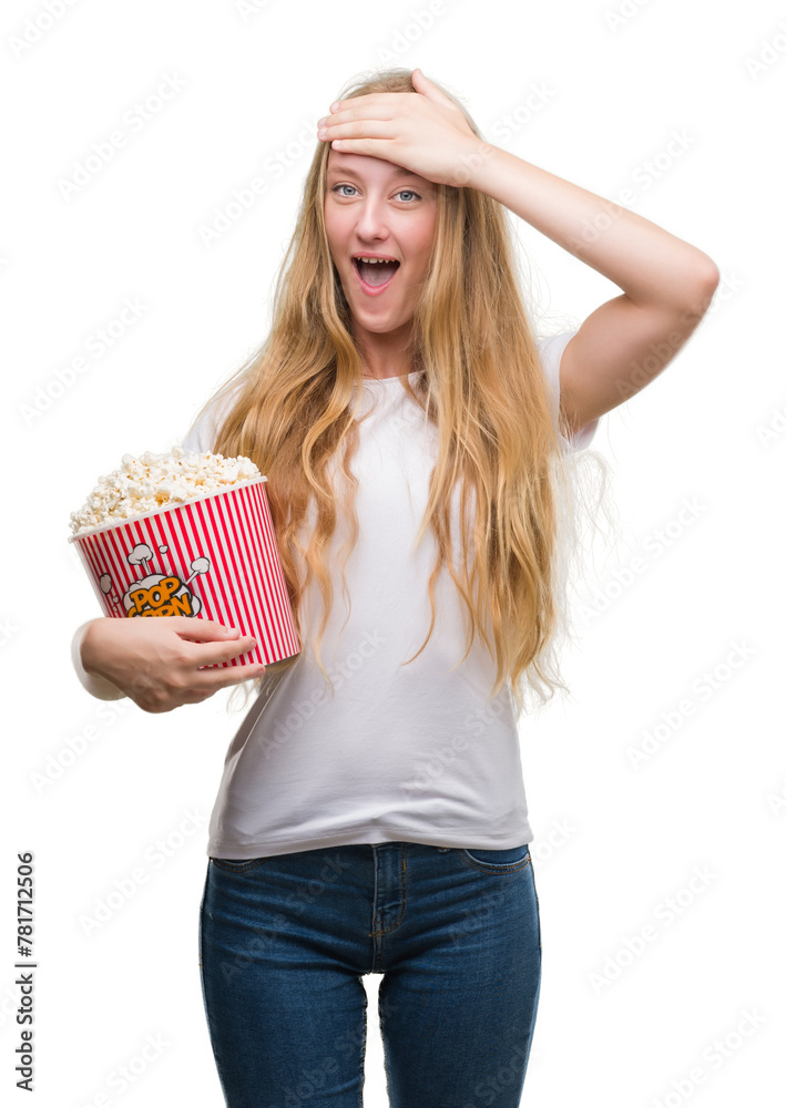Blonde teenager woman eating pop corn stressed with hand on head, shocked with shame and surprise face, angry and frustrated. Fear and upset for mistake. Blonde teenager woman eating pop corn stressed with hand on head, shocked with shame and surprise face, angry and frustrated. Fear and upset for mistake.