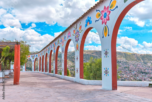 A long white archway with trees on either side, arch of Acuchimay, Ayacucho. Peru photo
