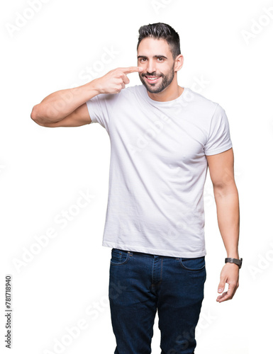 Young man wearing casual white t-shirt over isolated background Pointing with hand finger to face and nose, smiling cheerful