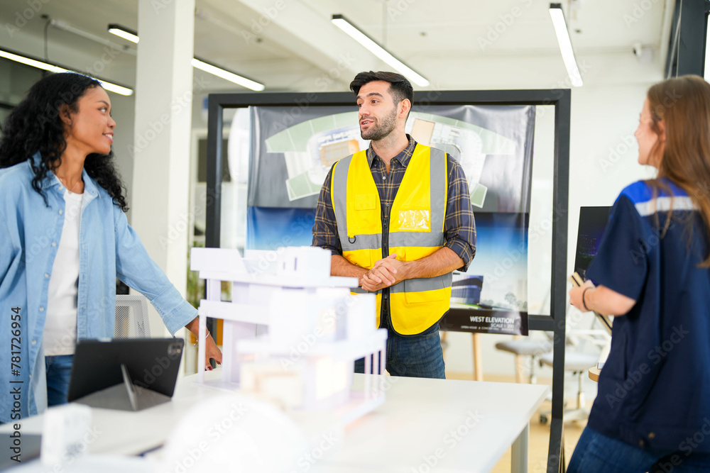 Architect and engineers wearing safety vests while analyzing solar power solutions over architectural plans. Architect and engineers wearing safety vests while analyzing solar power solutions over architectural plans.