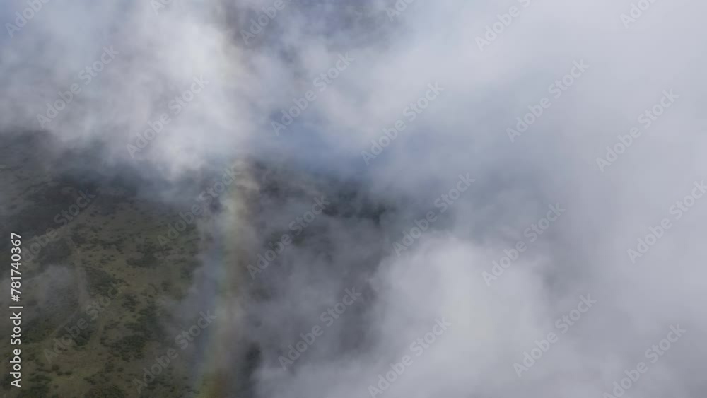 Aerial view of a colorful rainbow disappearing in white clouds over the landscape of Maui, Hawaii. Aerial view of a colorful rainbow disappearing in white clouds over the landscape of Maui, Hawaii.