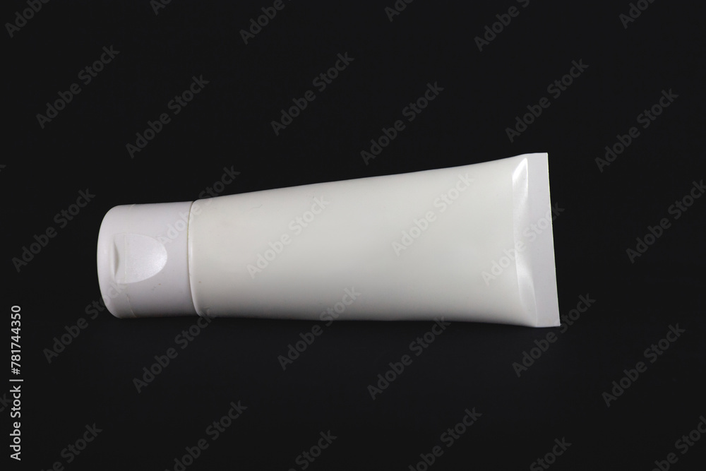 Studio shot of White cosmetics tube for cream and other skincare lotions isolated on a black background. Studio shot of White cosmetics tube for cream and other skincare lotions isolated on a black background.