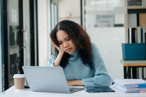 Woman who is tired and overthinking from working with tablet and laptop at modern office..