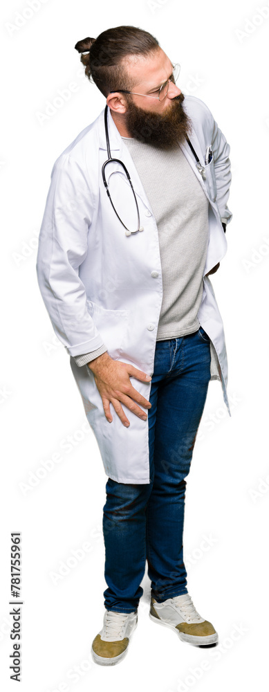 Young blond doctor man with beard wearing medical coat Suffering of backache, touching back with hand, muscular pain Young blond doctor man with beard wearing medical coat Suffering of backache, touching back with hand, muscular pain