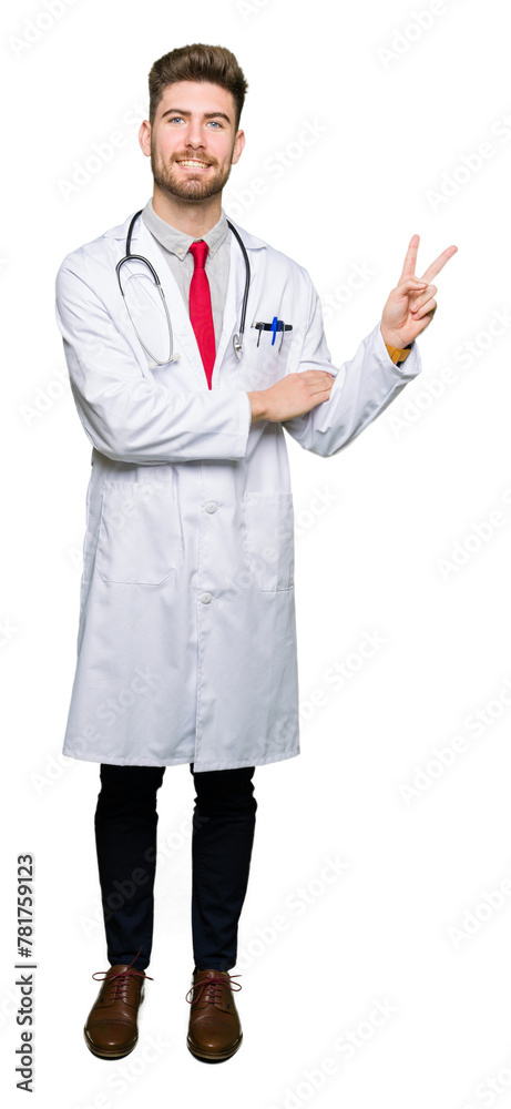 Young handsome doctor man wearing medical coat smiling with happy face winking at the camera doing victory sign. Number two.