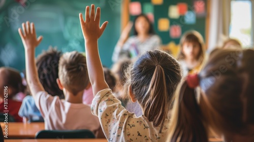 School kids raising hand in classroom at elementary school.