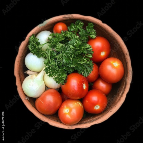 Top view of a bowl full of fresh vegetables, tomatoes, parsley, and onions isolated on black background.