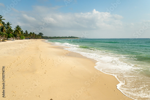 Beautiful background image of tropical beach. Bright summer sun over ocean. Blue sky light clouds, turquoise ocean with surf and clear sand. Harmony of clean environment.