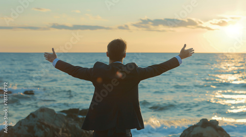 A man in a suit stands on the beach, arms outstretched, with the ocean in the background. Concept of freedom and relaxation, as the man is enjoying the beauty of the ocean