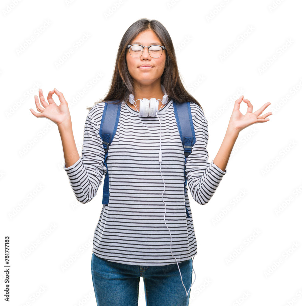 Young asian student woman wearing headphones and backpack over isolated background relax and smiling with eyes closed doing meditation gesture with fingers. Yoga concept. Young asian student woman wearing headphones and backpack over isolated background relax and smiling with eyes closed doing meditation gesture with fingers. Yoga concept.