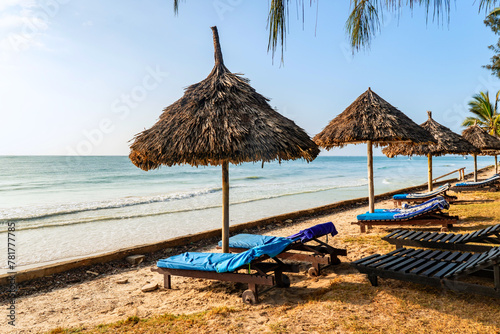 Umbrellas made of straw and chaise longue made of wood on a wonderful tropical beach, Beautiful beach, azure sea and white sand, blue sky and trees,