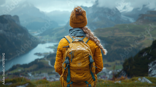 Girl with a yellow backpack looking at a beautiful view from the mountain.