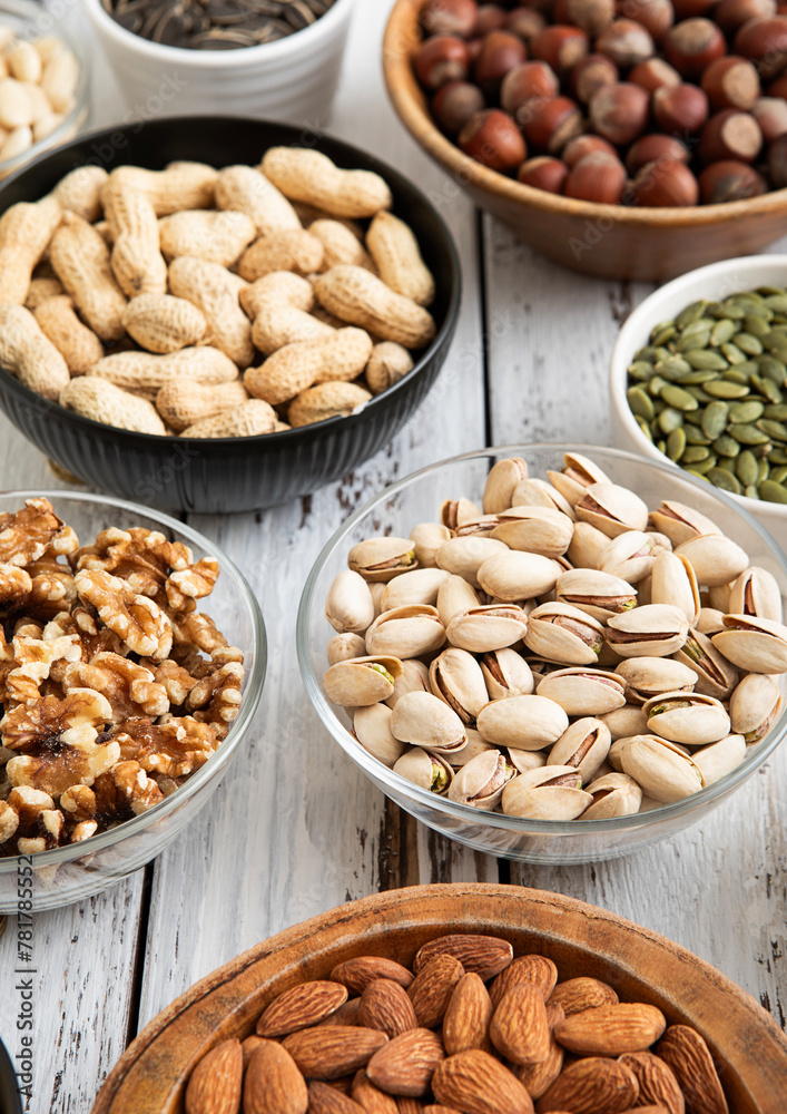 Mixed raw nuts and seeds in bowls on kitchen table.Peanut,hazelnut,walnut,almonds,pistachio,sunflower,pumpkin,chia and cashew.Macro Mixed raw nuts and seeds in bowls on kitchen table.Peanut,hazelnut,walnut,almonds,pistachio,sunflower,pumpkin,chia and cashew.Macro