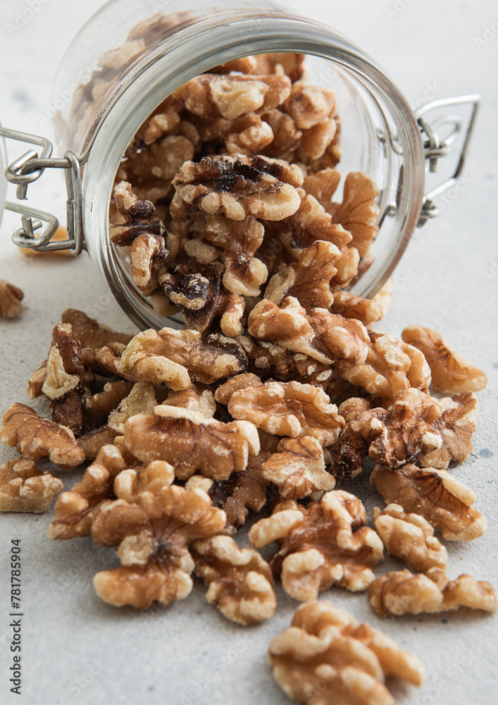 Obraz premium Raw healthy organic walnut nuts snack in glass jar on white kitchen table.Macro.