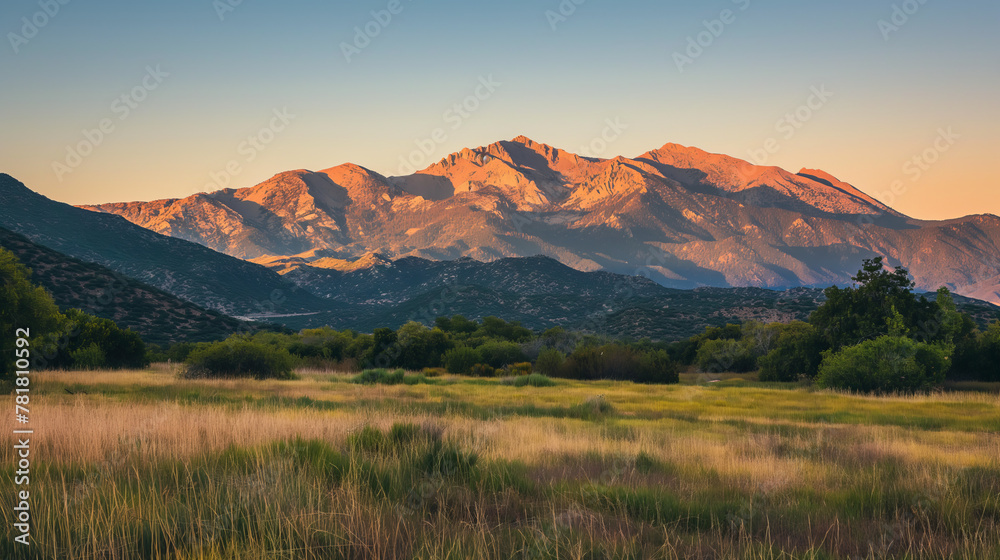 Golden sunlight on rugged mountains behind wide grasslands during the magical hour of sunset