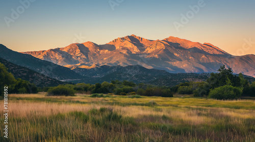 Golden sunlight on rugged mountains behind wide grasslands during the magical hour of sunset