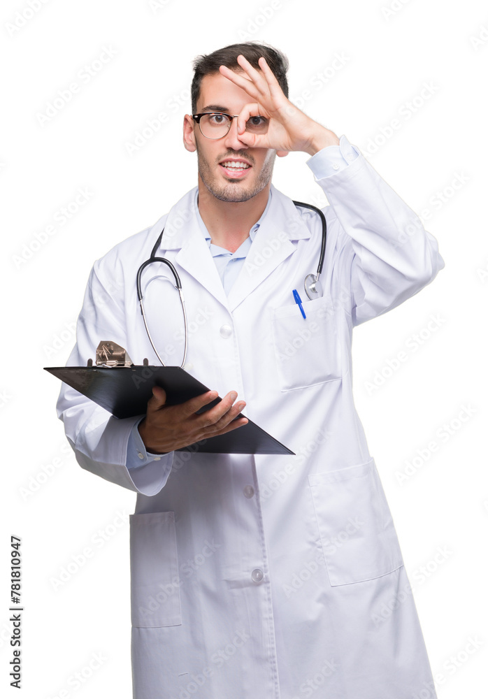 Handsome young doctor man holding a clipboard with happy face smiling doing ok sign with hand on eye looking through fingers Handsome young doctor man holding a clipboard with happy face smiling doing ok sign with hand on eye looking through fingers