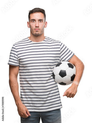 Handsome young man holding soccer football with a confident expression on smart face thinking serious