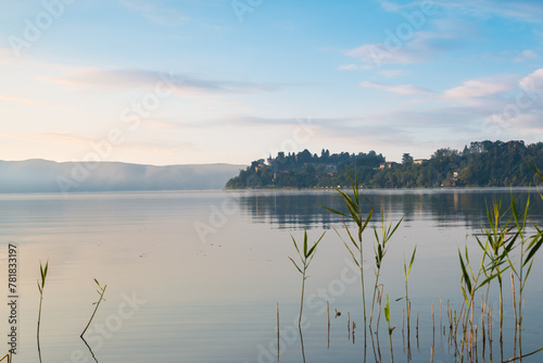 Sunrise on a lake in northern Italy. Lake Varese seen from Gavirate towards Biandronno. Frequented for fishing, rowing, walking and cycling along the 28 km cycle path around the lake