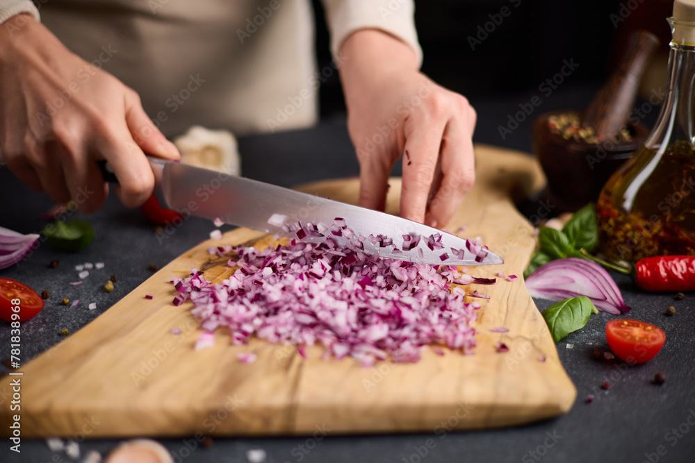 Woman chopping red Mars onion on wooden cutting board at domestic kitchen Woman chopping red Mars onion on wooden cutting board at domestic kitchen