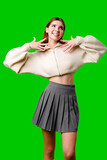 Smiling Young Woman in Casual Wear Posing With Hands on Neck Against Green Background