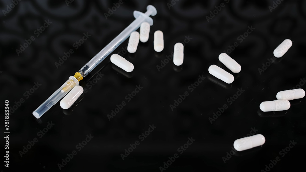White medecine Capsules to thin syringe that lies on black glass Background, slow motion. Medicine pill capsules crumble, close-up White medecine Capsules to thin syringe that lies on black glass Background, slow motion. Medicine pill capsules crumble, close-up