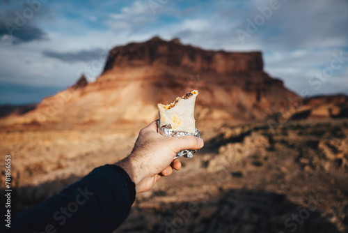 Holding a burrito in front of a butte in the desert photo