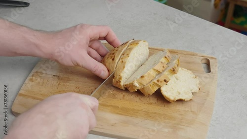 In the video, a man slices fresh white bread, creating footage suitable for cooking tutorials, bakery advertisements, and culinary shows