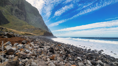 Breathtaking Madeira panorama - powerful cliffs, surging sea, foamy cascades, and lazy clouds. The contrast of raw nature with the blue sky amazes nature lovers