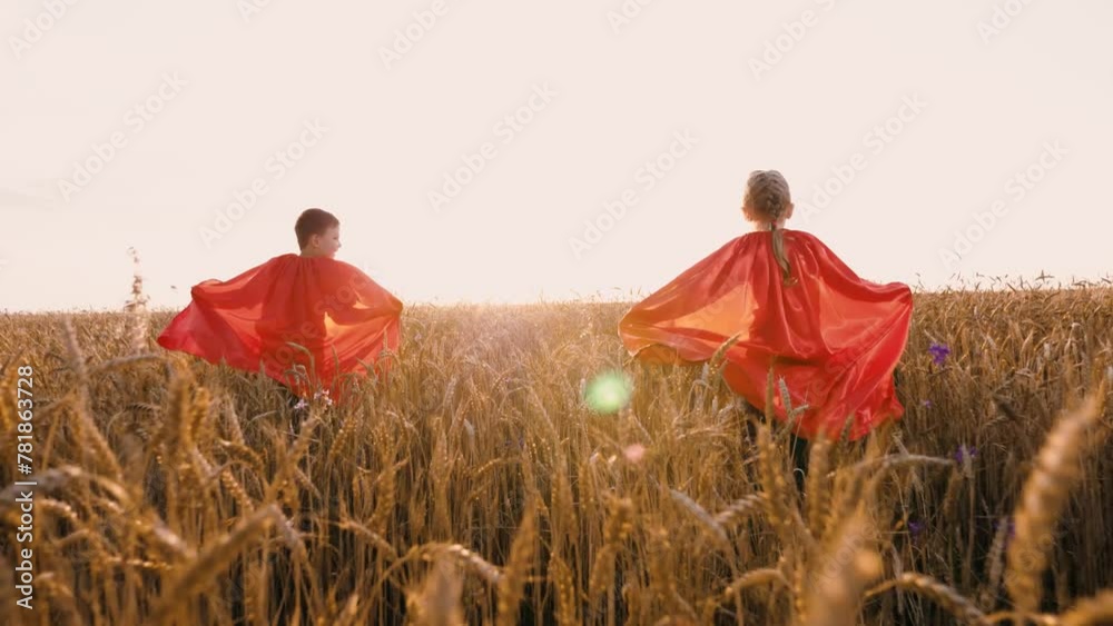 Happy kids in red superhero cloak running at sunlight dry wheat field ...