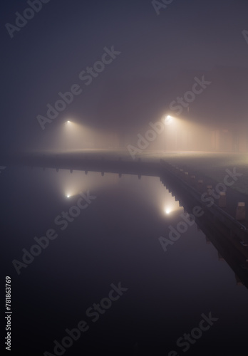 A suburb and streetlights at the waterfront in the dense fog.
