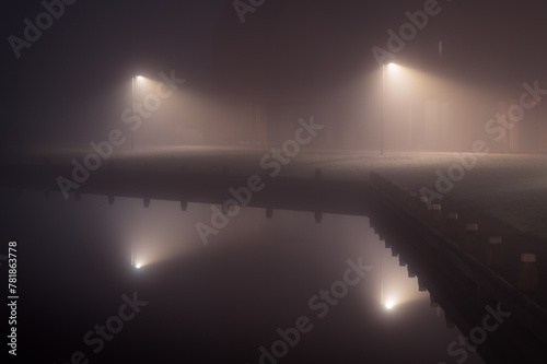 Streetlights in a suburb at the waterfront in the dense fog.