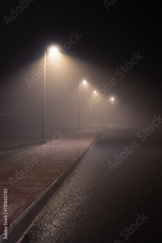 Streetlights in a suburb in the dense, spring fog. © sanderstock
