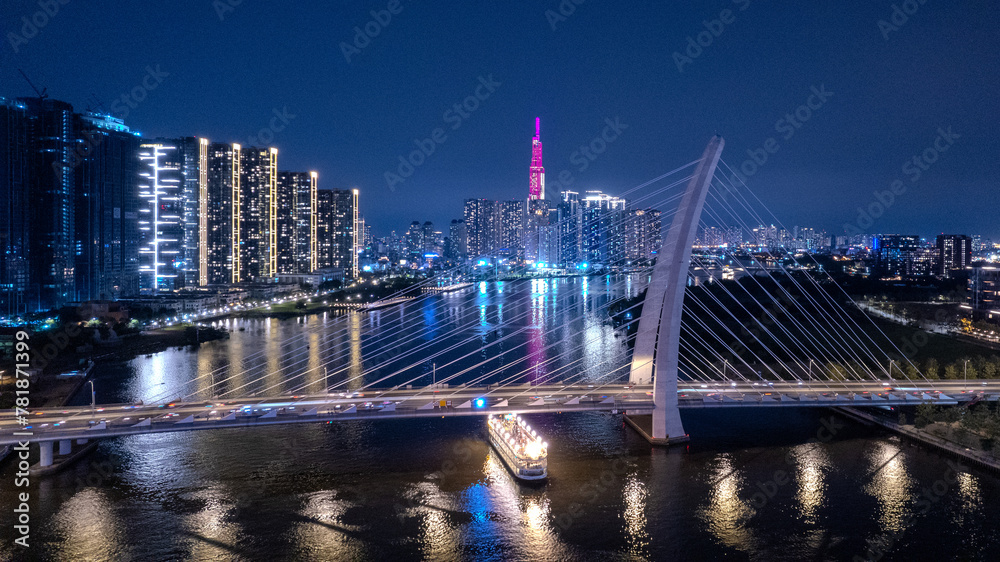 Obraz premium Aerial night, Mekong river delta view of a bridge, illuminated Saigon city skyline skyscrapers view and busy traffic on the main road of Ho Chi Minh