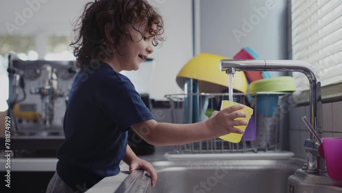 Young child having fun playing with water in the sink in a modern kitchen