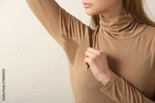 Close up image of woman in beige cotton turtleneck with sweat patch under armpit