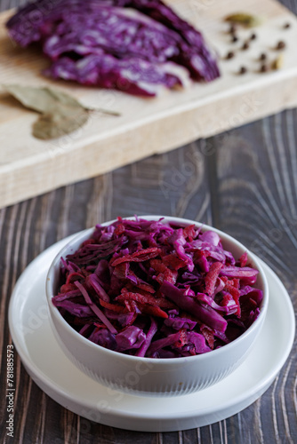 Homemade pickled red cabbage in white ceramic bowl. Vertical, close up