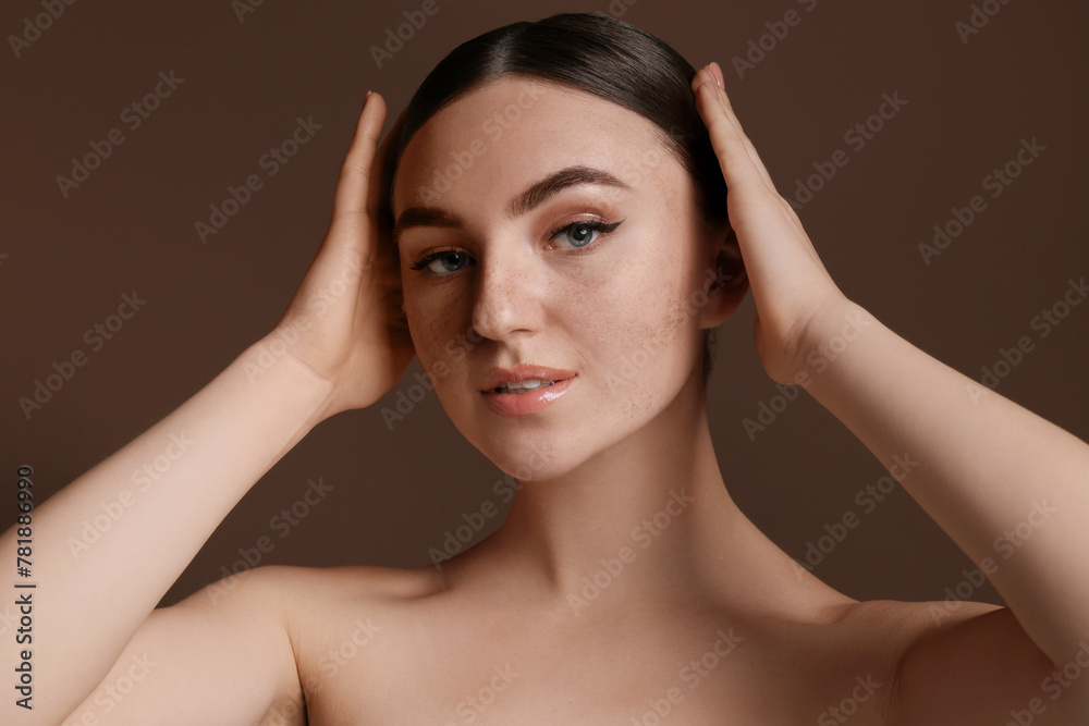 Fototapeta premium Portrait of beautiful woman with fake freckles on brown background