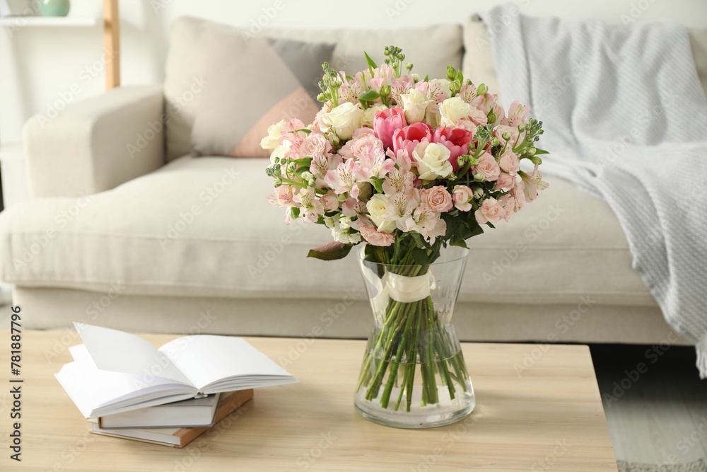 Beautiful bouquet of fresh flowers in vase and books on wooden table indoors Beautiful bouquet of fresh flowers in vase and books on wooden table indoors